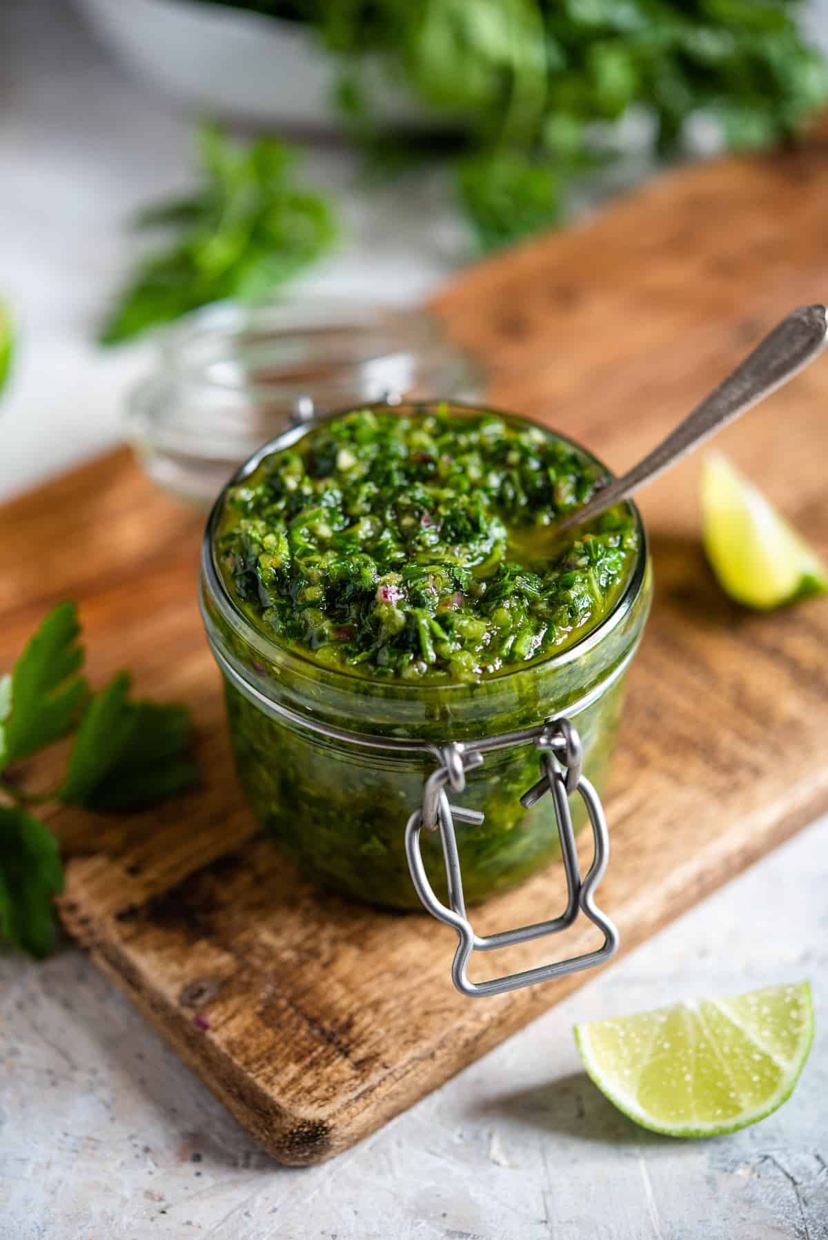 A spoon resting in a mason jar filled with Cilantro Chimichurri