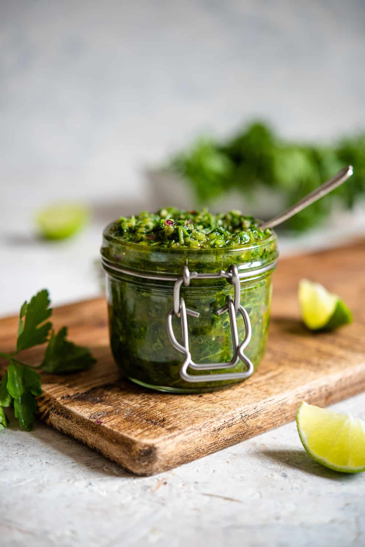 A mason jar filled with Cilantro Chimichurri on a wood board.