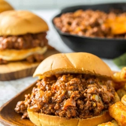 A sloppy joe and tater tots on a wooden plate.