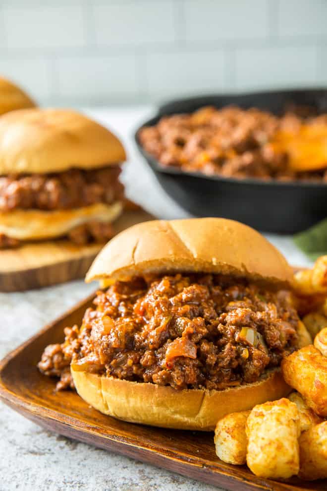 A Cajun Sloppy Joe on a brown serving plate with tater tots