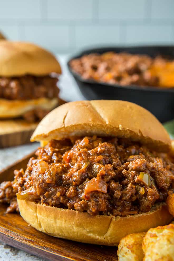 A closeup of a sloppy joe on a wooden plate.