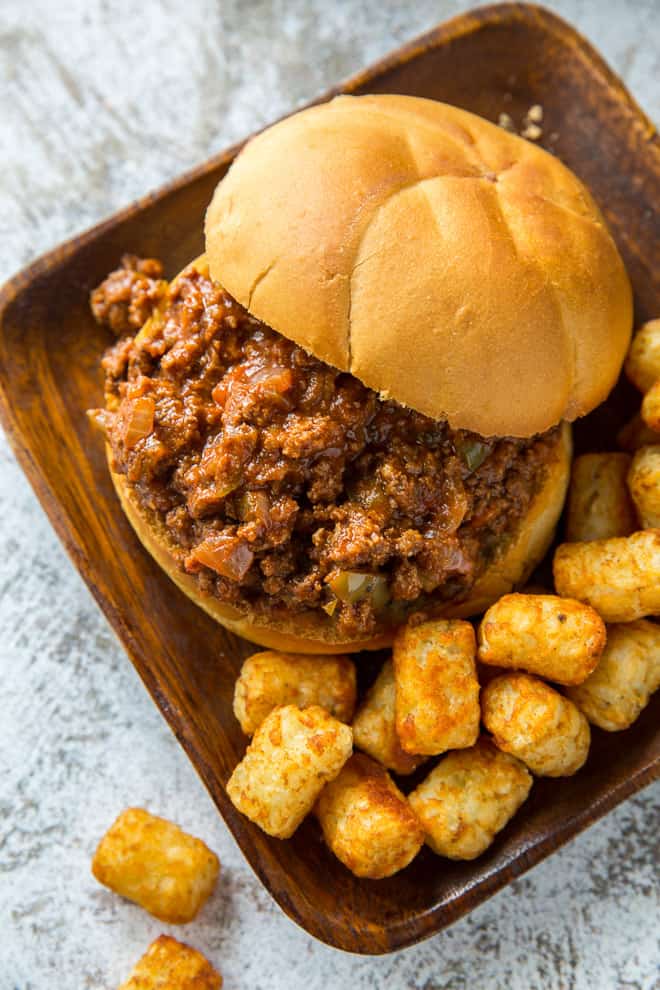A Cajun Sloppy Joe on a brown serving plate with tater tots.