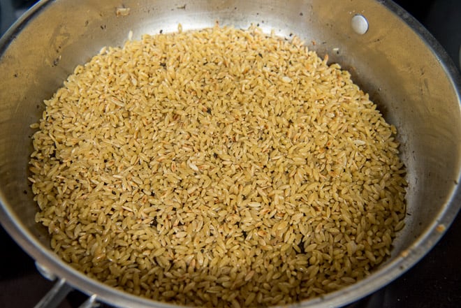 Orzo being toasted in oil in a saute pan.