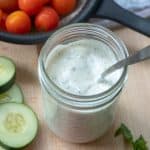 A mason jar filled with creamy Ranch dressing with a spoon.