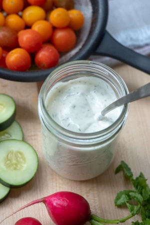 A mason jar filled with creamy Ranch dressing with a spoon.