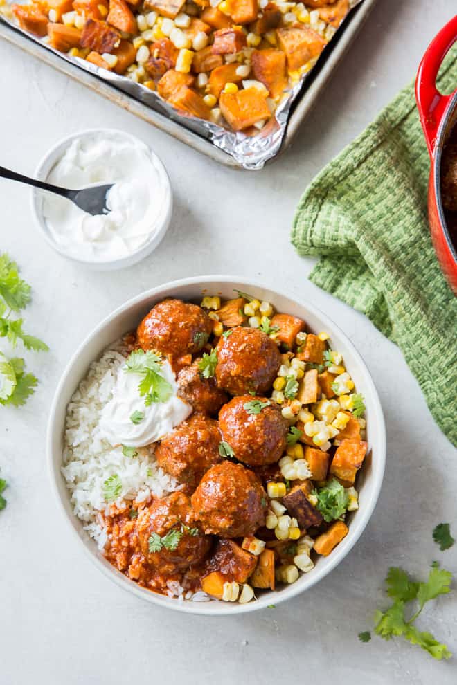 Tex-Mex Meatballs in a white bowl over rice with sweet potatoes and corn shot from over the top.