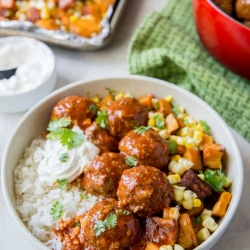 A bowl of filled with rice, meatballs, and vegetables.