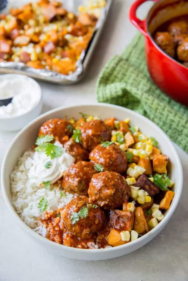 A bowl of filled with rice, meatballs, and vegetables.