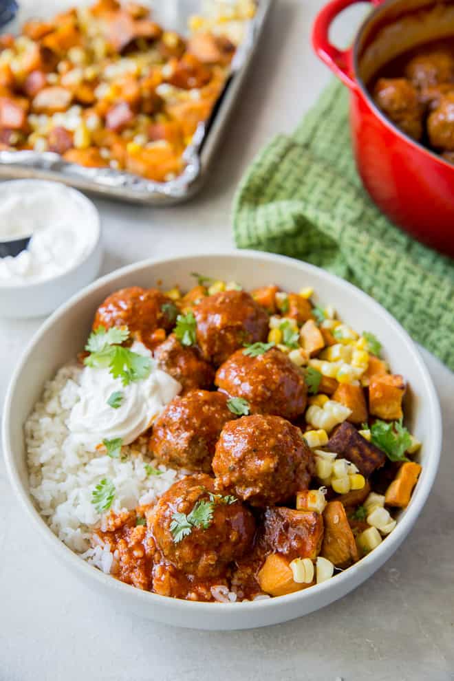 A bowl of filled with rice, meatballs, and vegetables.