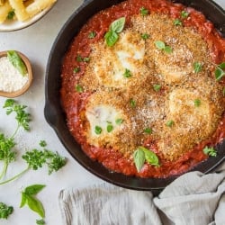 A skillet filled with tomato sauce, chicken, and mozzarella cheese.