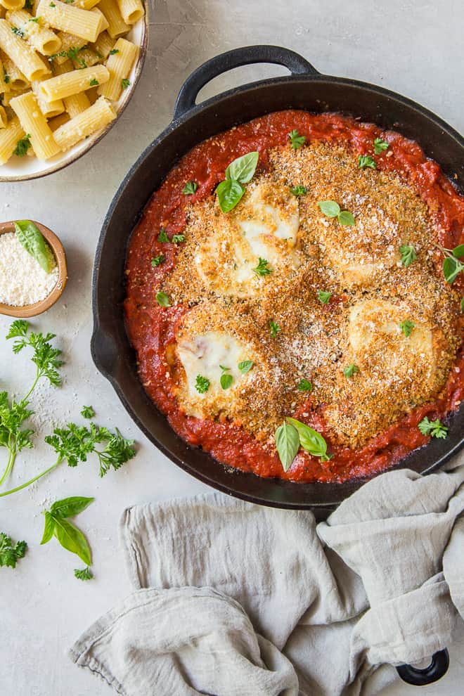 A skillet filled with tomato sauce, chicken, and mozzarella cheese.