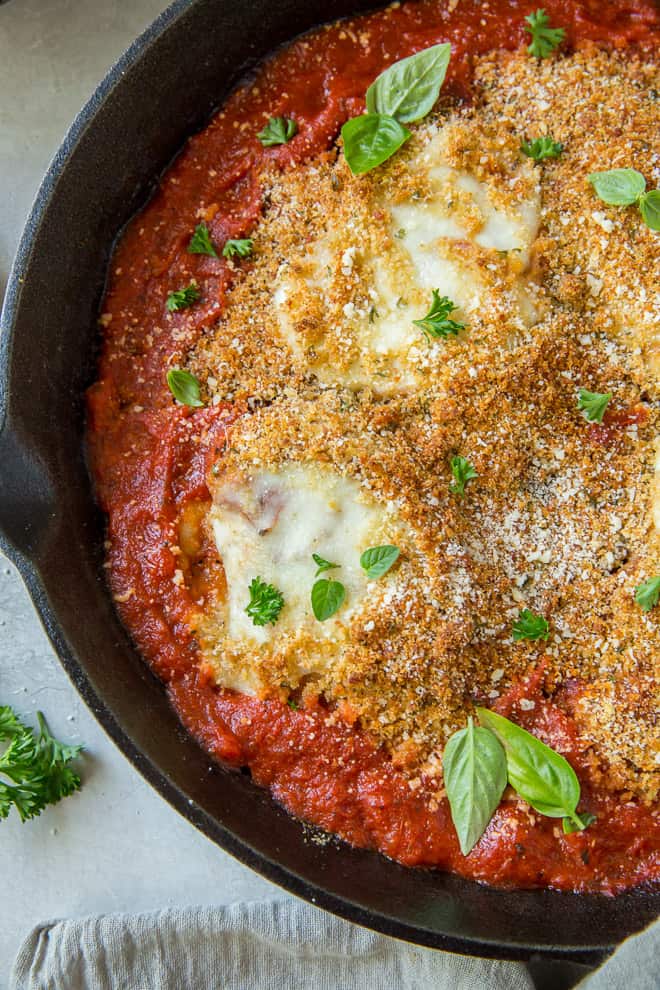 A close up shot of a cast iron skillet full of Chicken Parmesan