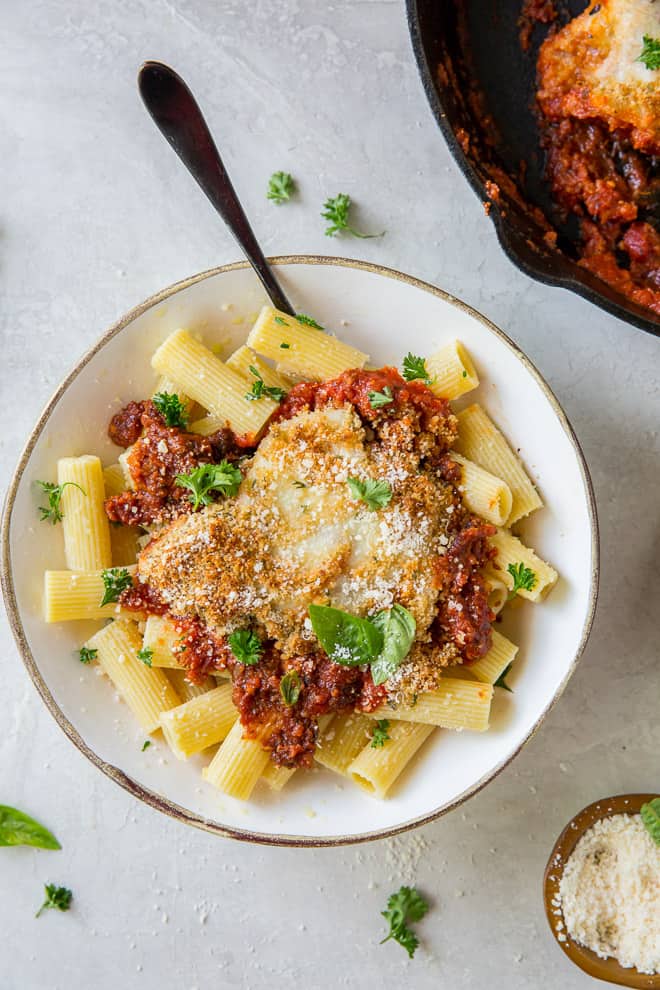 A serving of Skillet Chicken Parmesan in a white serving bowl with a fork.