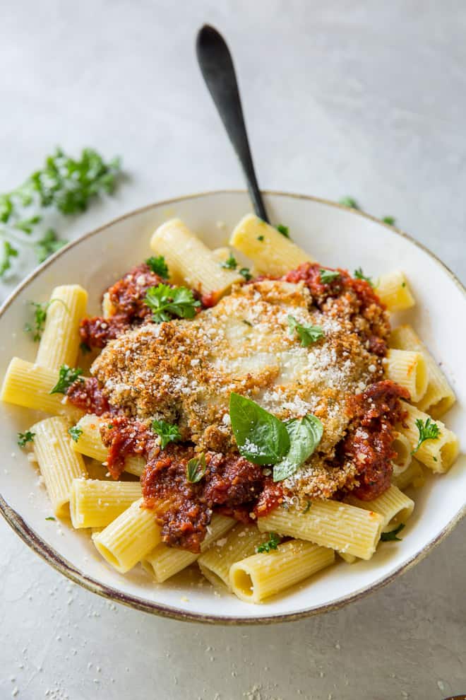 A white serving bowl filled with Skillet Chicken Parmesan.