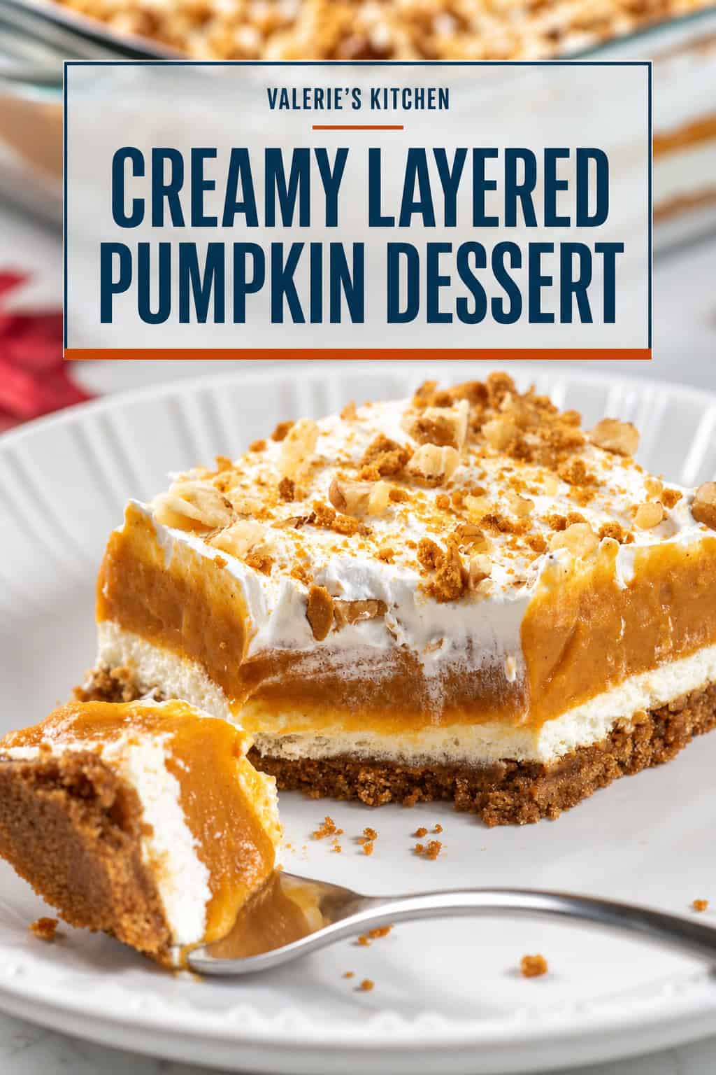 A slice of creamy layered pumpkin dessert with gingersnap crust, cream cheese and pumpkin layers, whipped topping, and crushed gingersnaps and walnuts. Text overlay reads “Creamy Layered Pumpkin Dessert.”