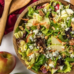 A large wooden bowl filled with salad with apples and cabbage.