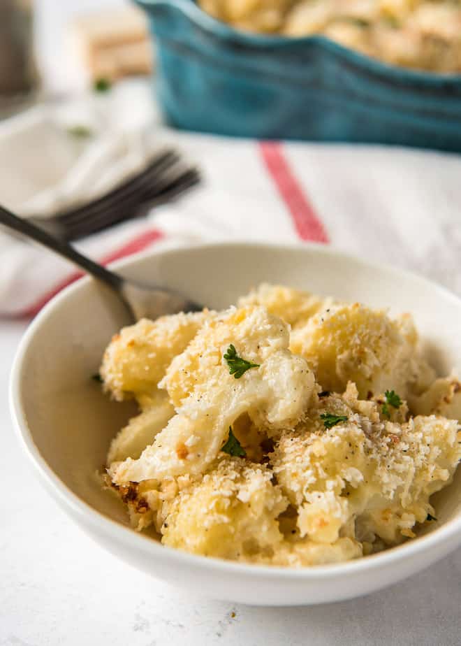 A serving of Cauliflower Gratin in a small white bowl with a fork.