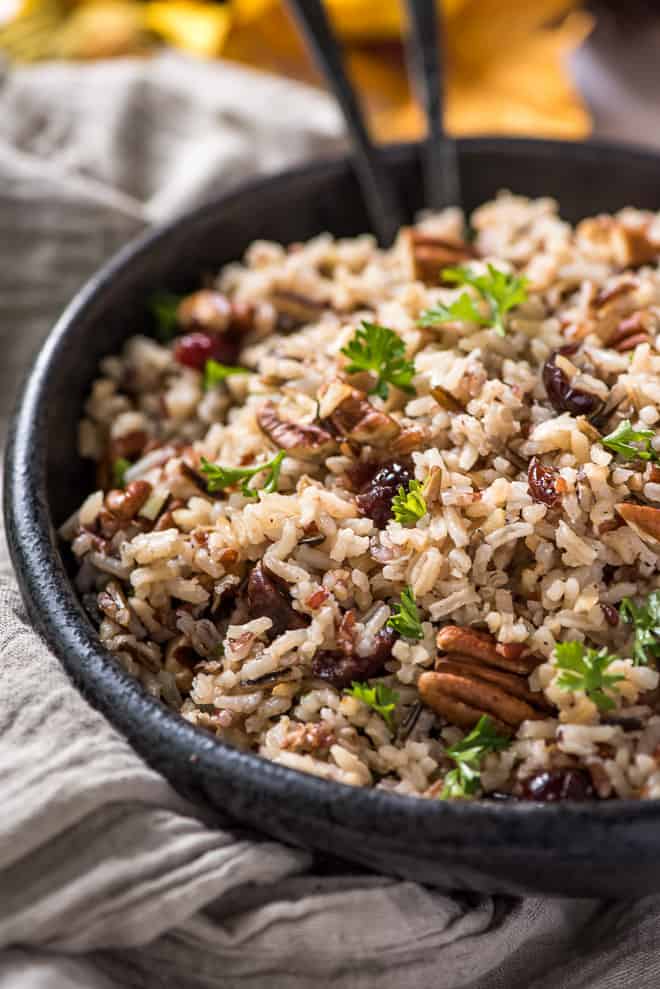 A black bowl filled with wild rice and pecans.