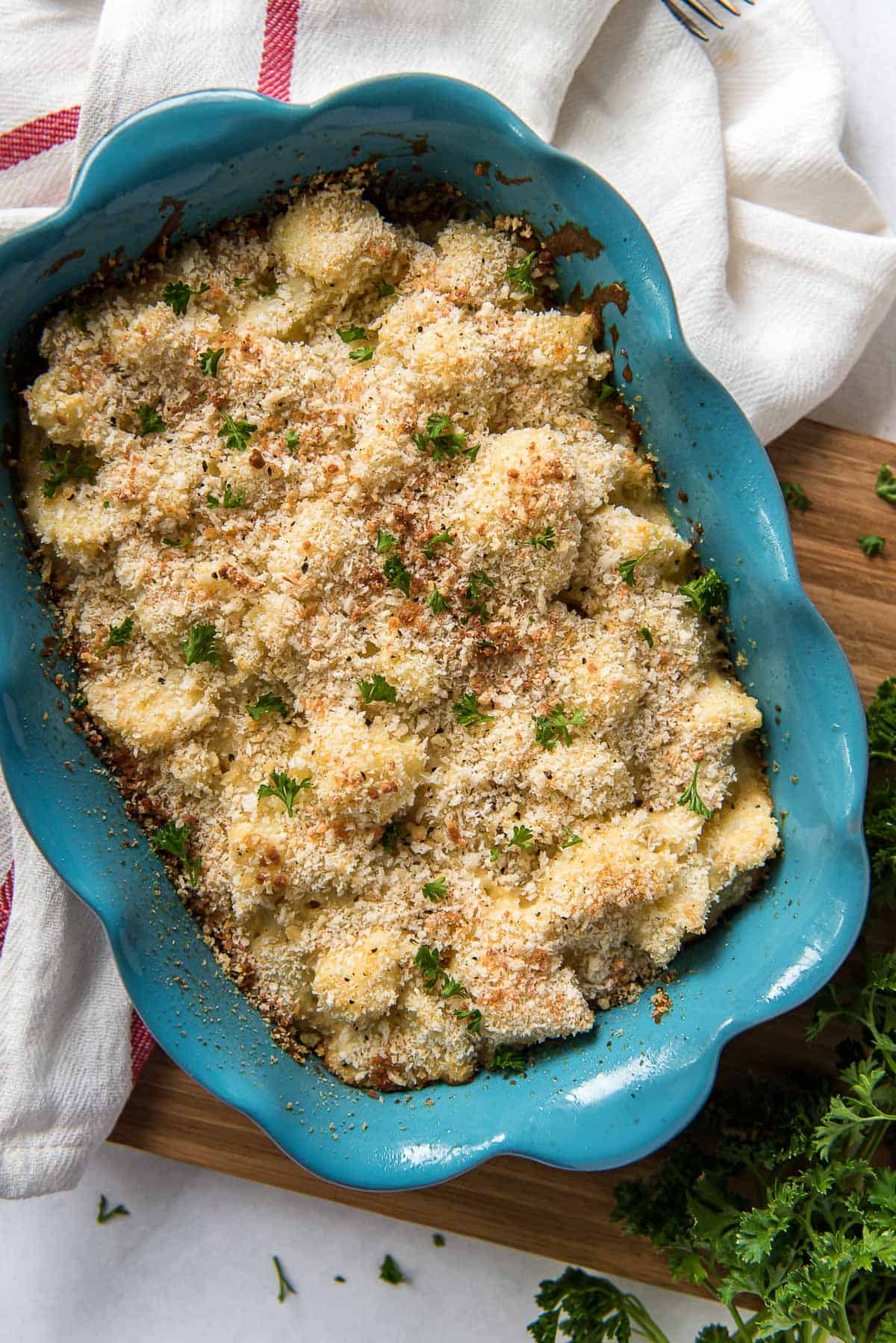 Caulifower casserole topped with bread crumbs in a blue casserole dish.