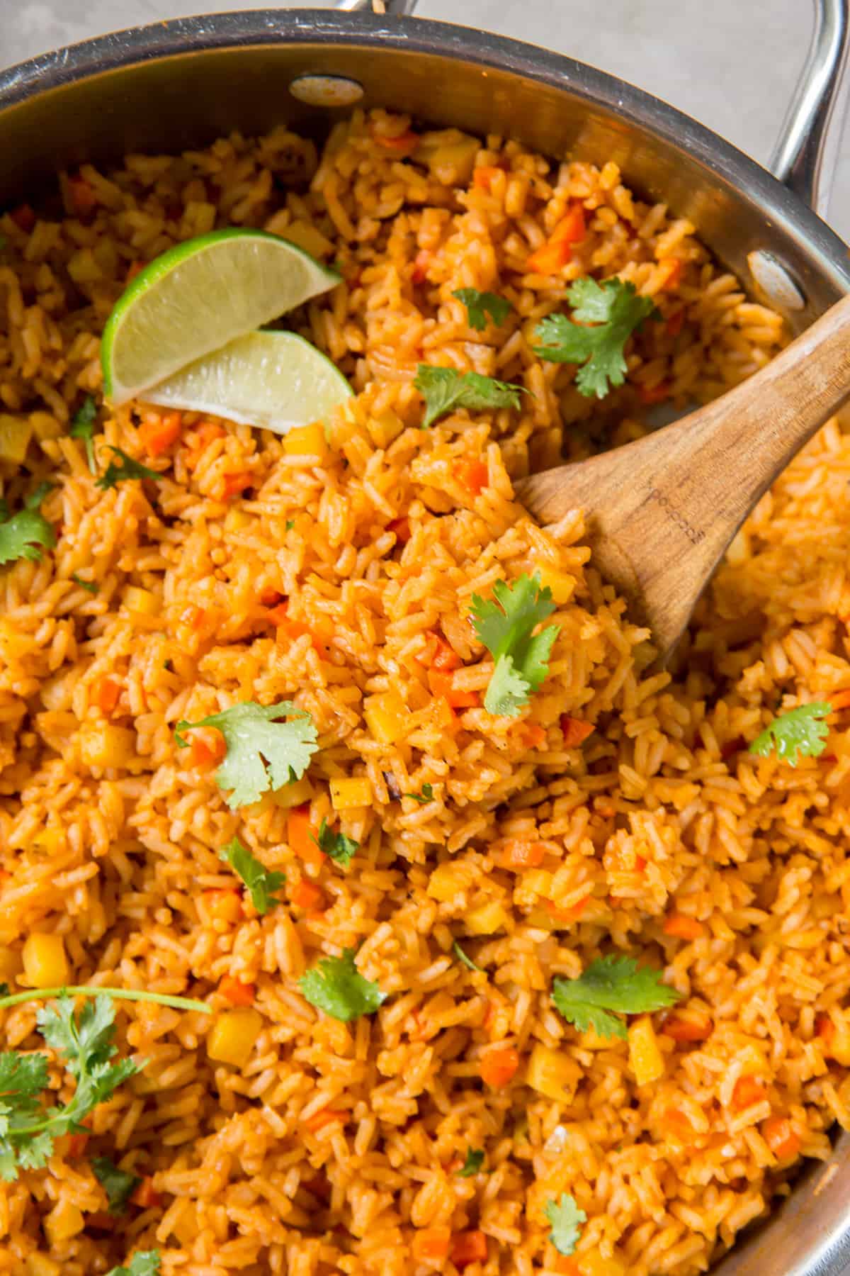 A top down shot of a spoon scooping Mexican rice from a skillet.