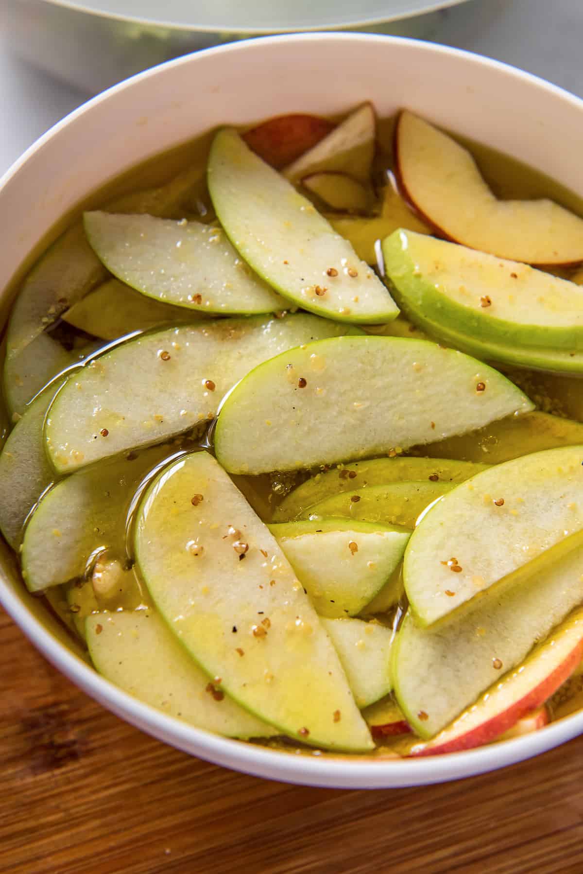Apples soaking in a vinegar salad dressing in bowl.