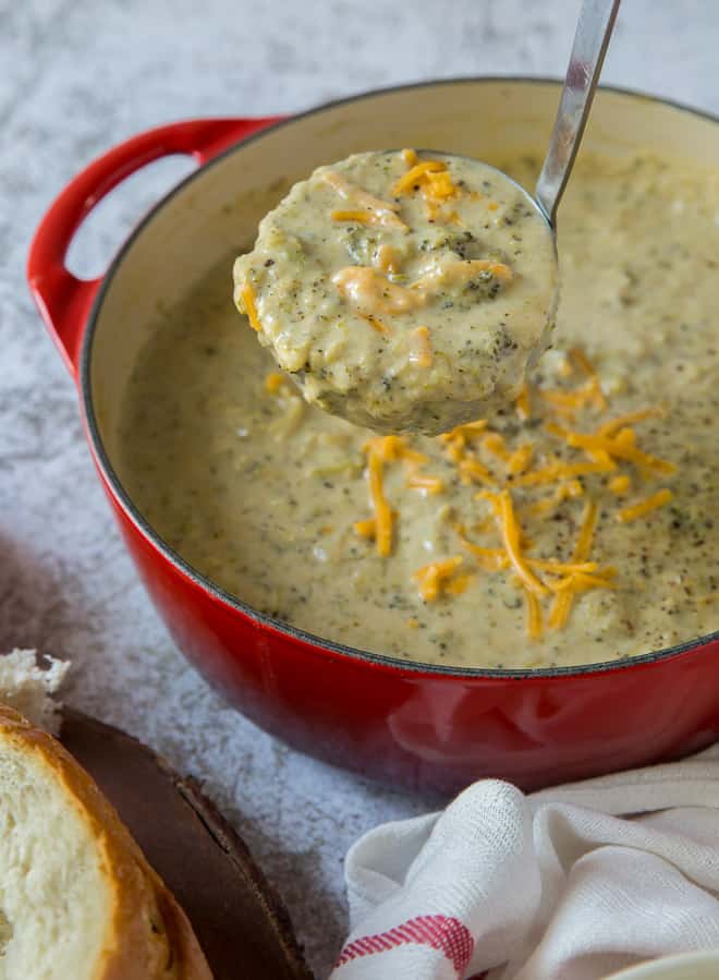 A ladle of Broccoli Cheese Soup being lifted from a pot.