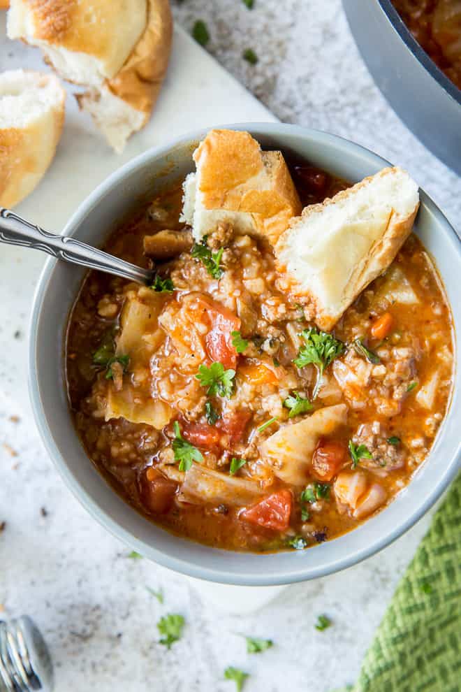 Torn pieces of bread are dunked into a bowl of Cabbage Roll Soup.