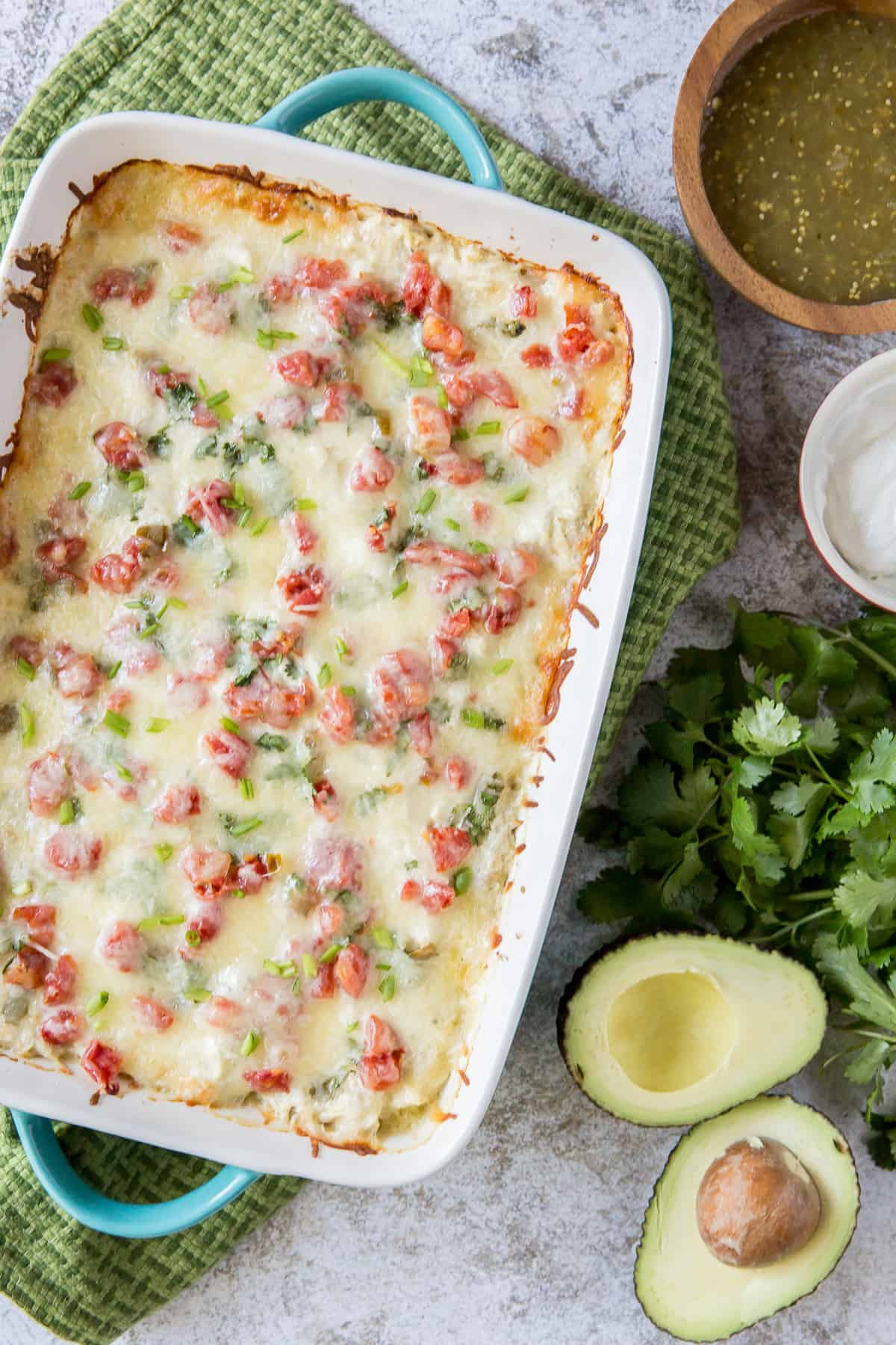 A chicken tortilla casserole with tomatoes in a white dish.