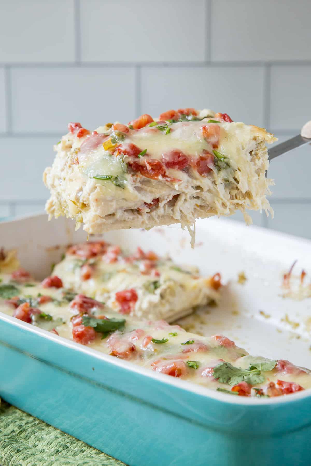 A spatula lifting a scoop of Chicken Tortilla Casserole from a baking dish.