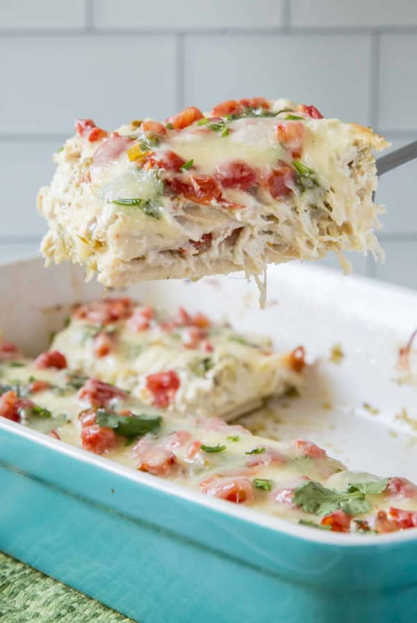 A spatula lifts a slice of chicken tortilla casserole from a baking dish.