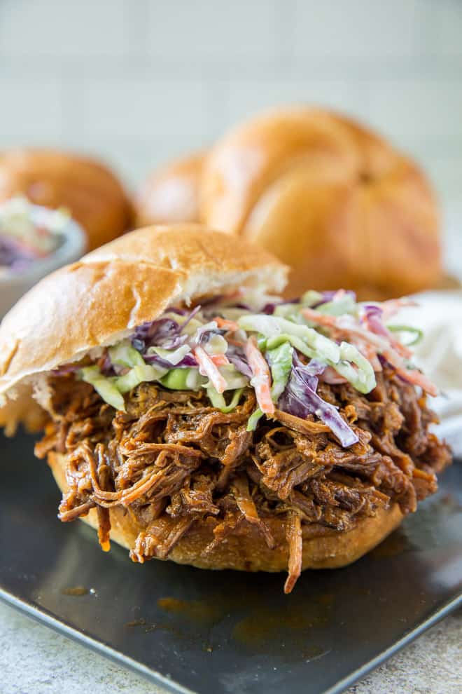 Coleslaw is layered over the top of shredded BBQ Beef on a toasted bun.