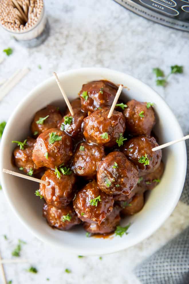 Cocktail meatballs in a white serving bowl with toothpicks inserted in the center.