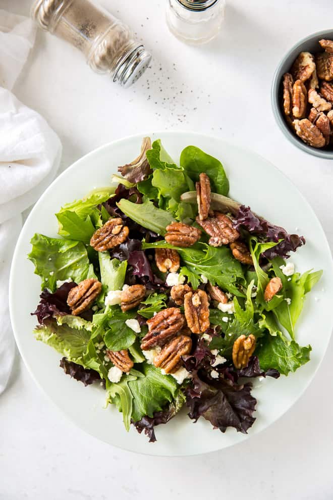 A simple green salad topped with glazed nuts and cheese.