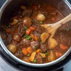 A wooden spoon in an Instant Pot full of Beef Stew.