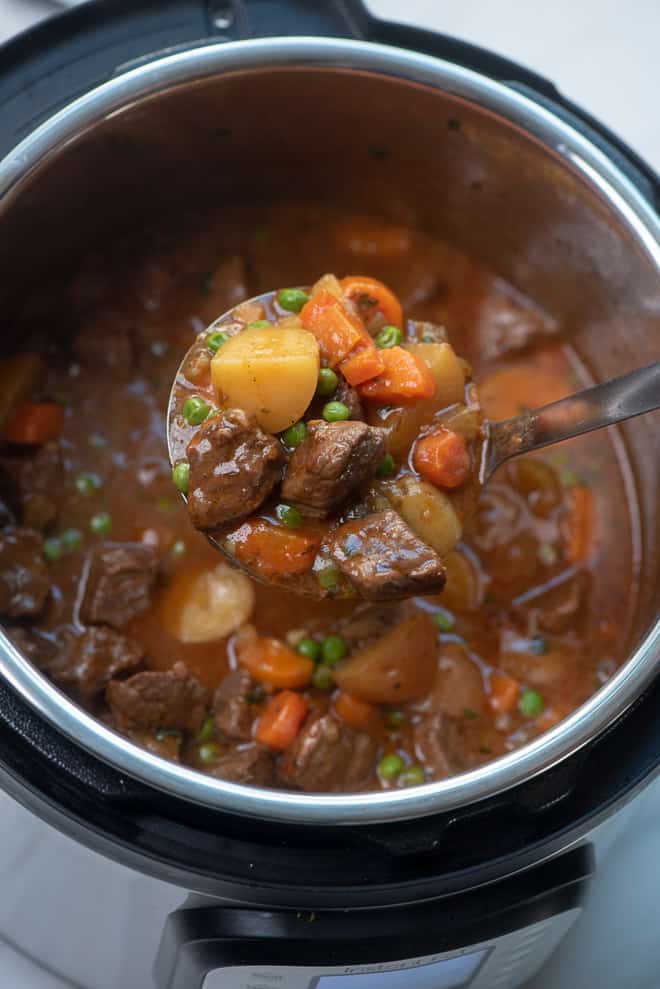 A ladle scoops some beef stew from an Instant Pot.