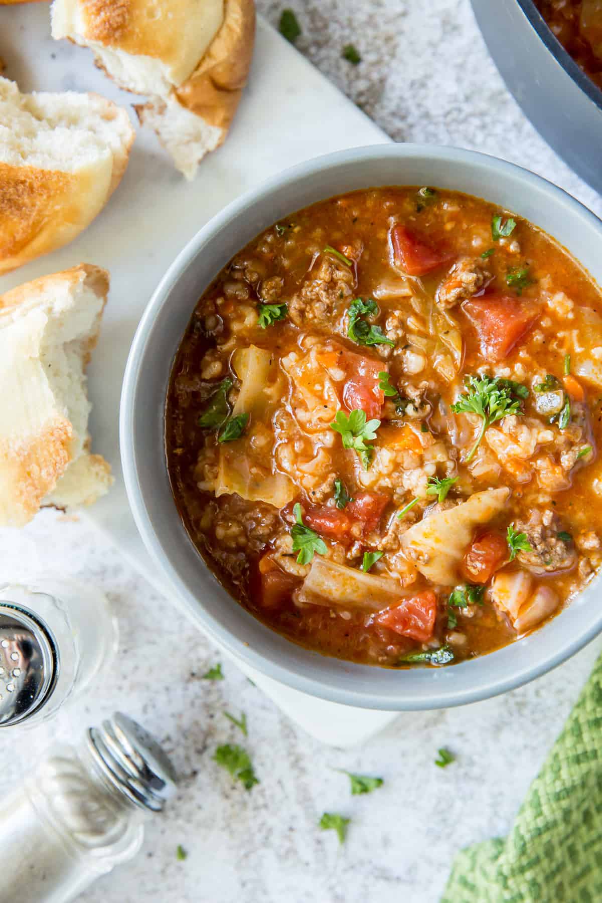 A bowl of soup with rice, cabbage, and tomatoes.