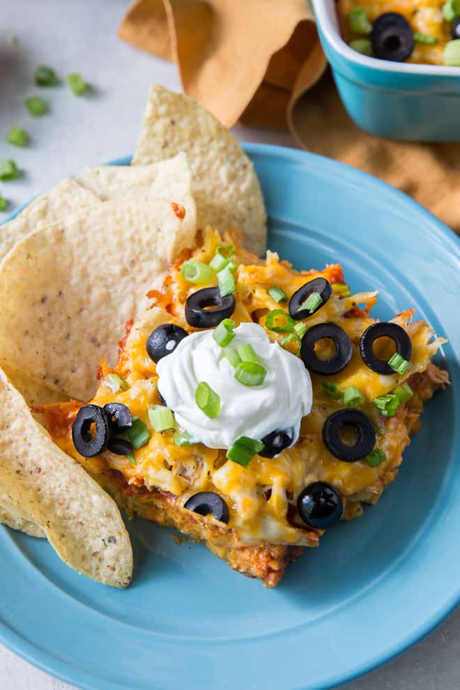 A close up image of the Chicken Tortilla Casserole on a blue plate with tortilla chips.