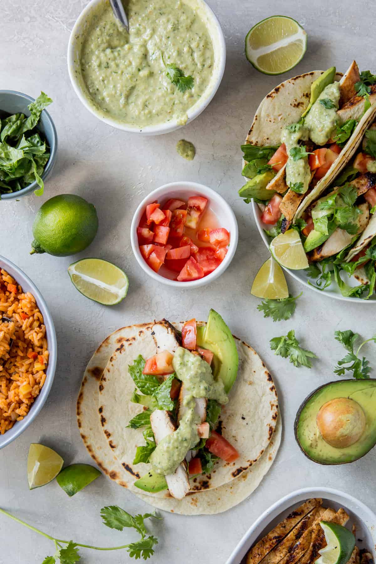 A top down shot of taco toppings in bowls and tacos on a plate.