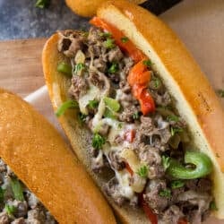 A close up of a cheesesteak sandwich with peppers and onions.