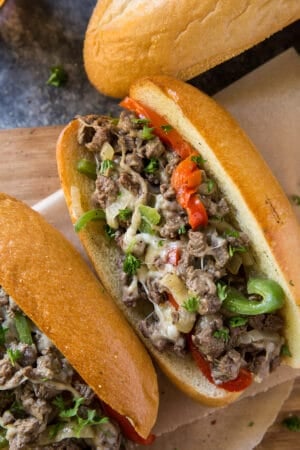 A close up of a cheesesteak sandwich with peppers and onions.