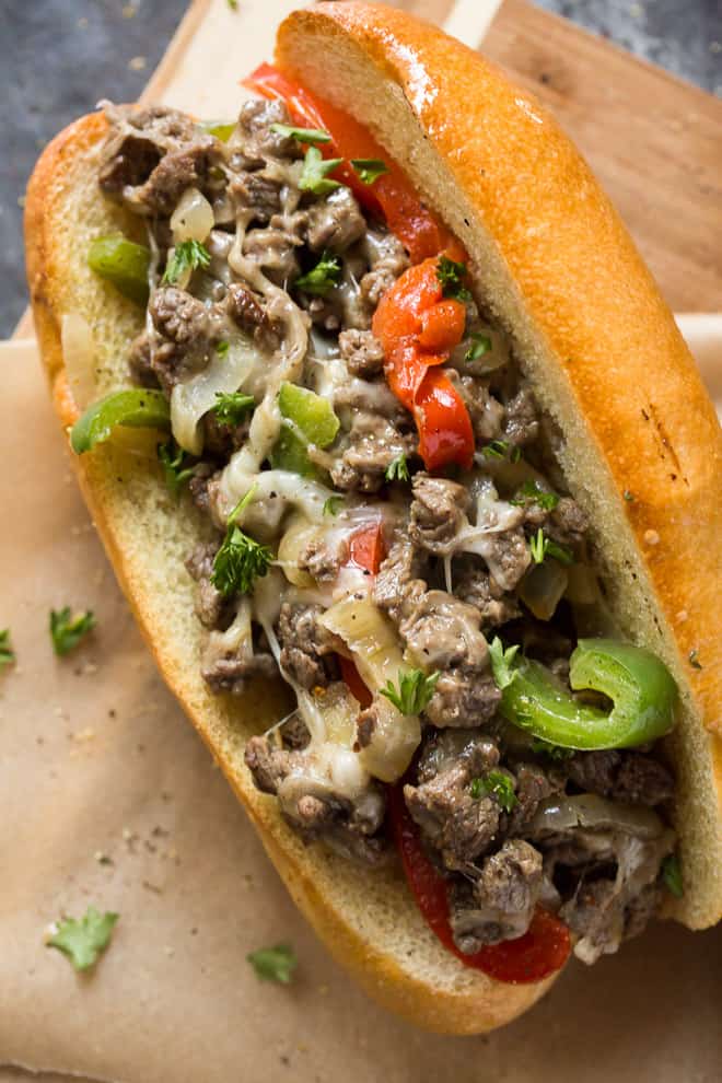 A close up image of a Philly Cheesesteak with Peppers and Onions on a toasted hoagie roll.