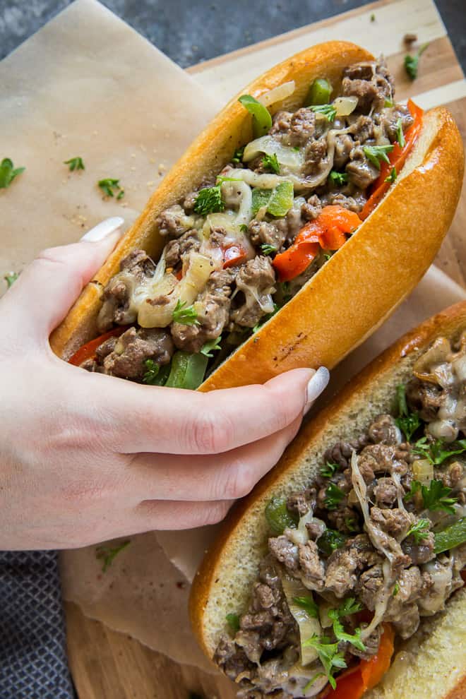 A hand holding a Philly Cheesesteak Sandwich.