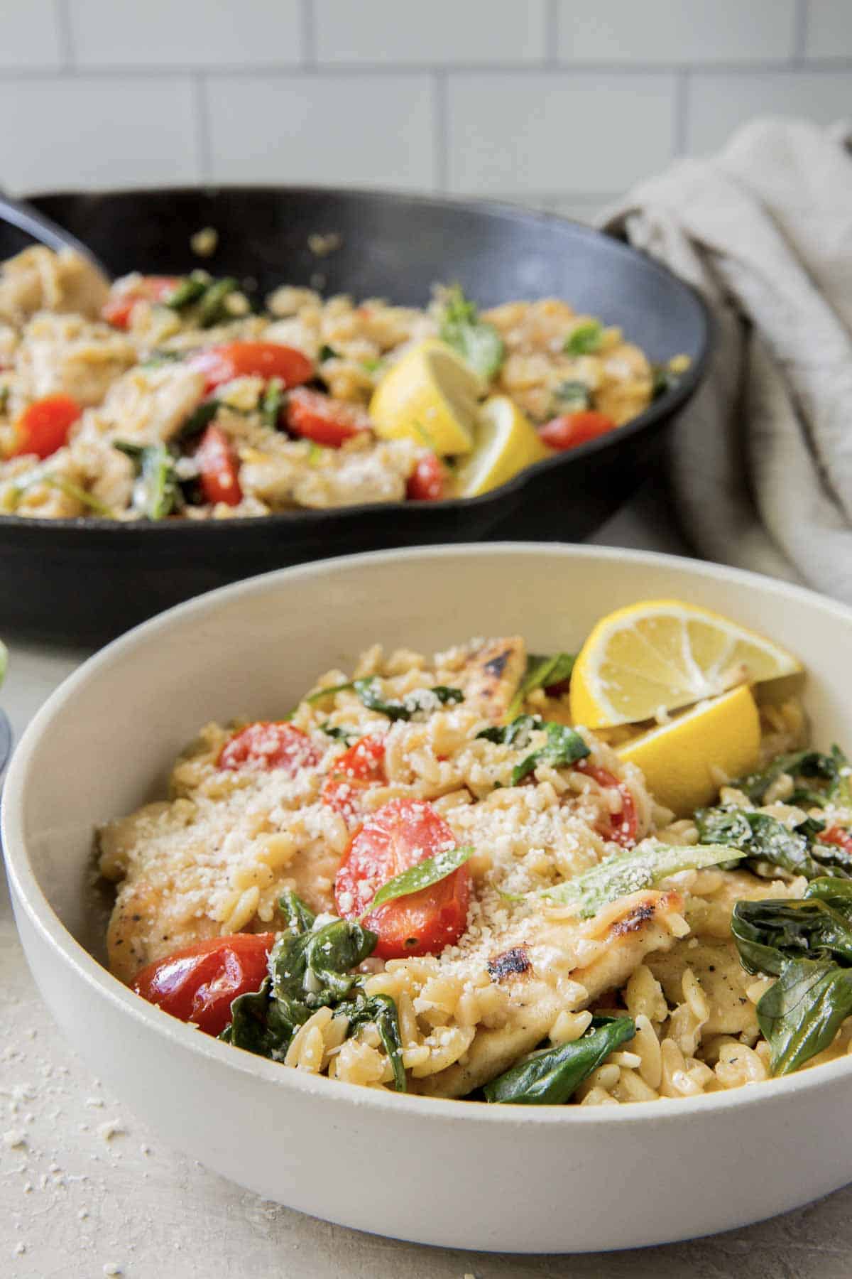A serving of lemon chicken with orzo in a white bowl.