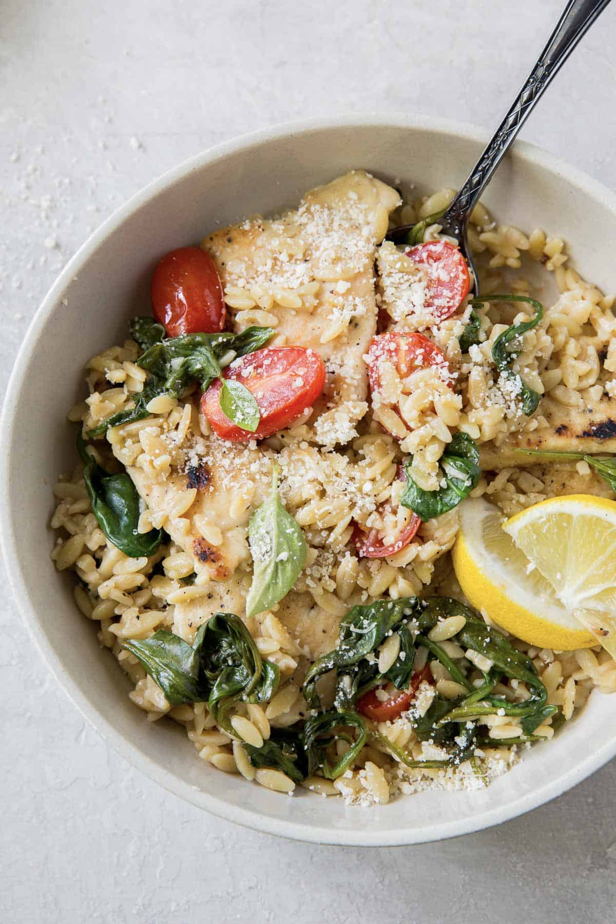 A fork resting in a bowl of lemon chicken with orzo.