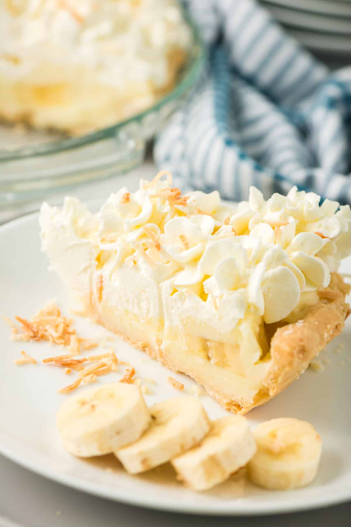 A slice of Banana Cream Pie on a serving plate with sliced bananas.