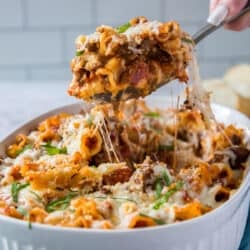 A spoon lifts a scoop of the lasagna casserole from the dish.