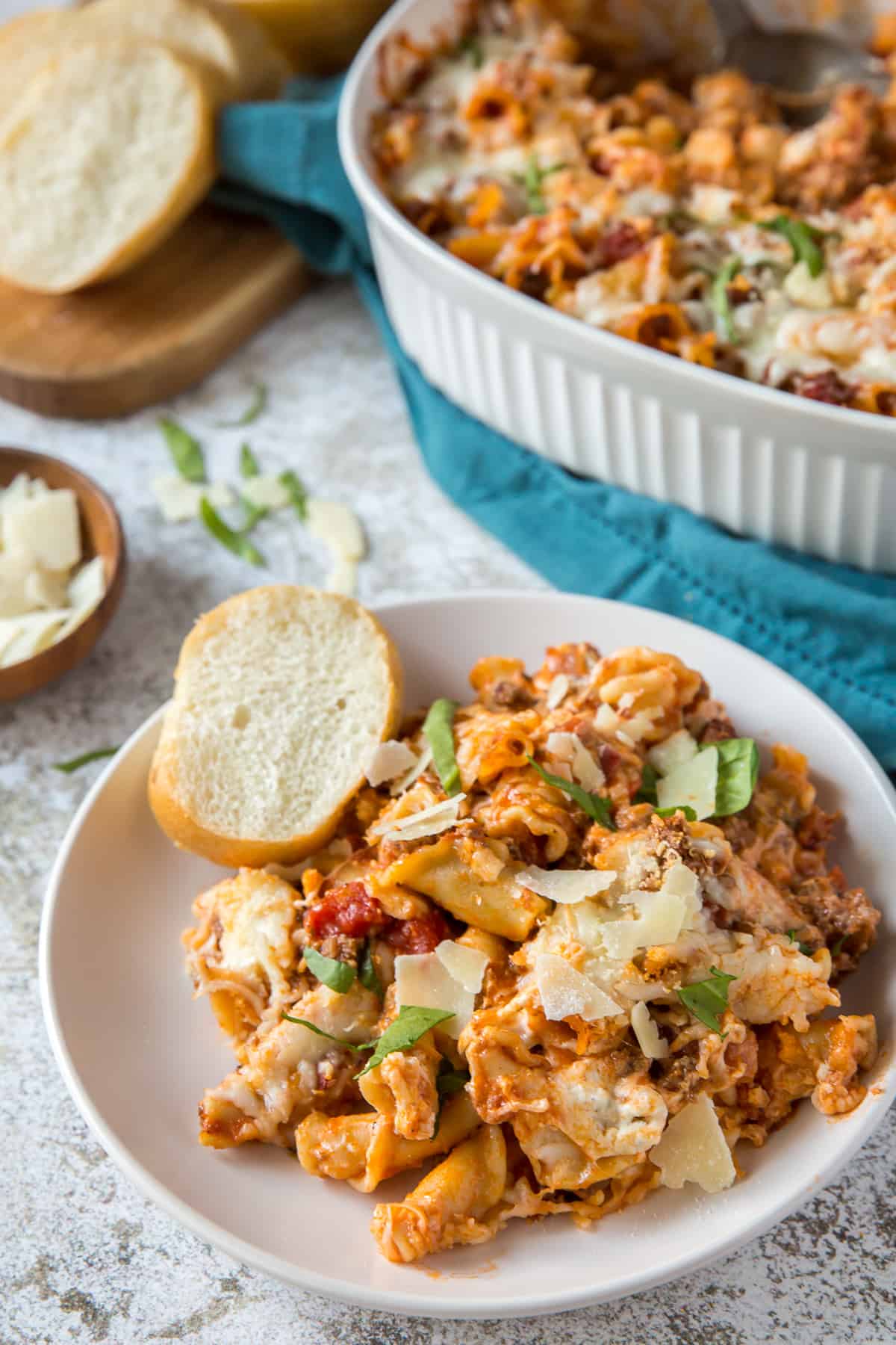 A white serving plate with a serving of the lasagna casserole and a slice of French bread.