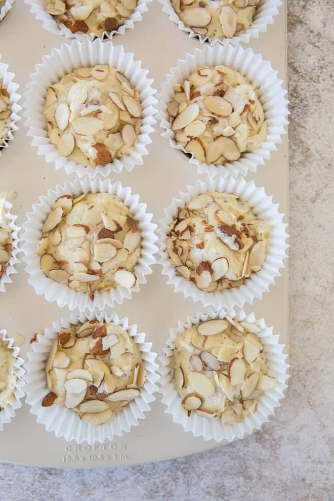 An overhead shot of the Lemon Almond Poppy Seed muffin batter topped with sugar and almonds in the muffin pan.