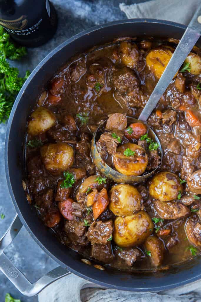 A ladle scoops up some stew from a pot.
