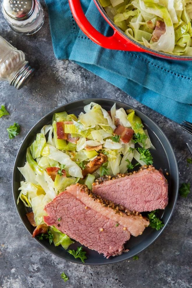 An overhead shot of a plate of Sauteed Cabbage with Leeks and Bacon with slices of corned beef.